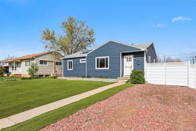 ranch-style home with a front lawn, a shingled roof, driveway, and fence