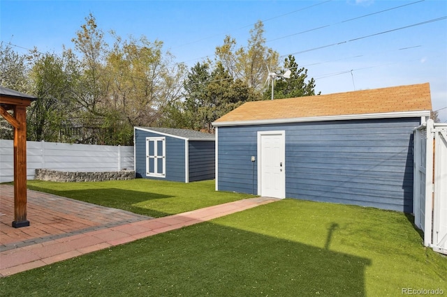 view of yard featuring a storage unit, a patio area, fence, and an outbuilding