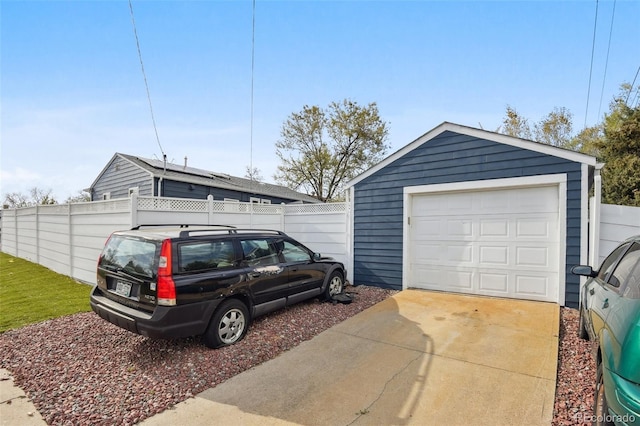 detached garage with fence and concrete driveway