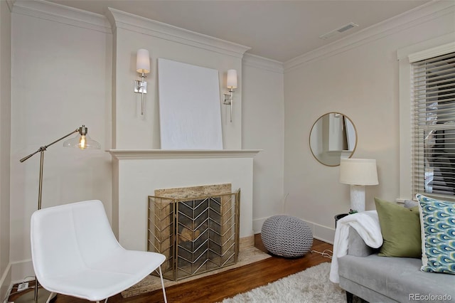 interior space with a fireplace with flush hearth, visible vents, crown molding, and wood finished floors