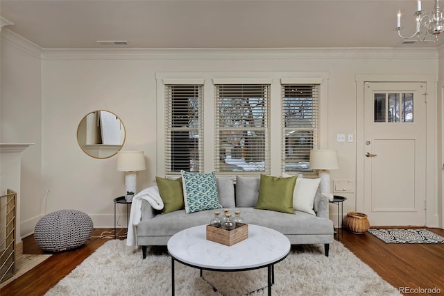 living area featuring visible vents, a chandelier, dark wood-type flooring, and ornamental molding