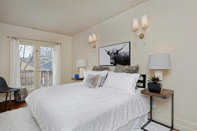 bedroom featuring baseboards, visible vents, ornamental molding, wood finished floors, and french doors