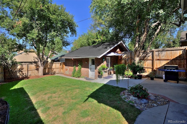 view of front of house with an outbuilding, a fenced backyard, brick siding, a front lawn, and a patio area