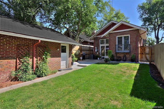 back of property with a yard, central AC, brick siding, and fence