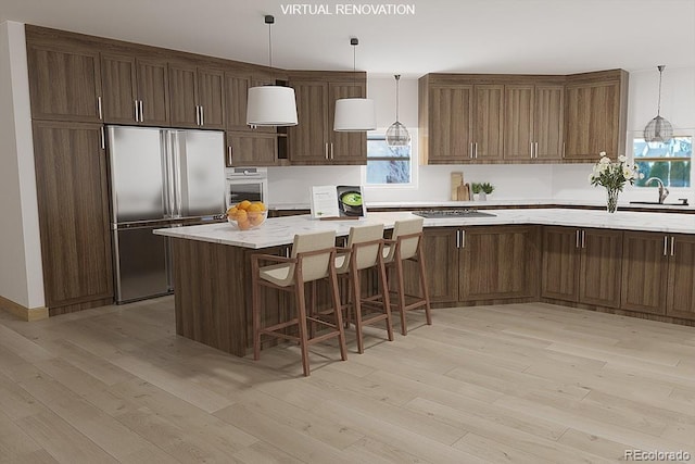 kitchen featuring hanging light fixtures, appliances with stainless steel finishes, light wood-type flooring, and light stone countertops