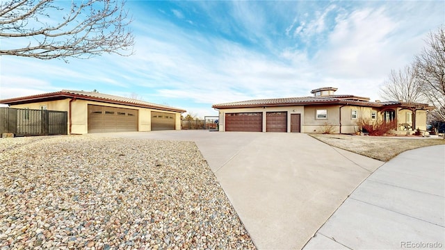 view of front of property featuring fence, a tiled roof, concrete driveway, stucco siding, and a garage