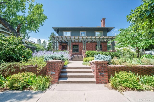 view of front of property with a pergola, a chimney, and brick siding