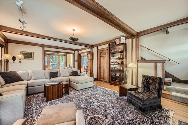 living area featuring track lighting, light wood-type flooring, stairway, and beam ceiling