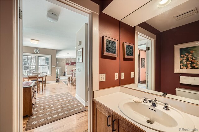 bathroom featuring toilet, wood finished floors, vanity, visible vents, and baseboards