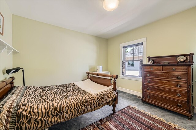 bedroom featuring dark colored carpet and baseboards