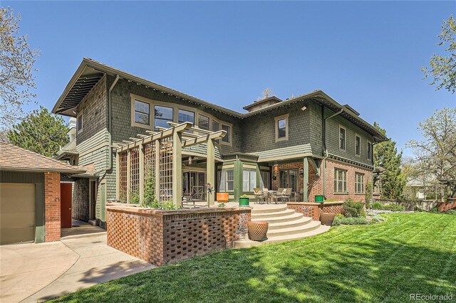 back of property with a lawn, brick siding, a patio area, and a garage
