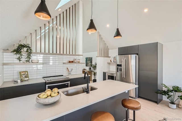 kitchen featuring appliances with stainless steel finishes, decorative light fixtures, lofted ceiling, sink, and a kitchen bar