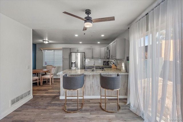 kitchen with gray cabinetry, a sink, visible vents, appliances with stainless steel finishes, and dark wood finished floors