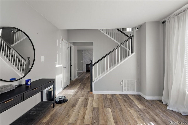 entrance foyer with stairs, wood finished floors, visible vents, and baseboards