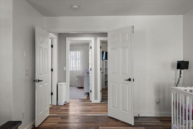 corridor featuring baseboards and dark wood finished floors