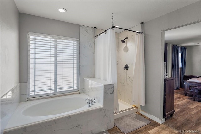 bathroom with a garden tub, a stall shower, and wood finished floors