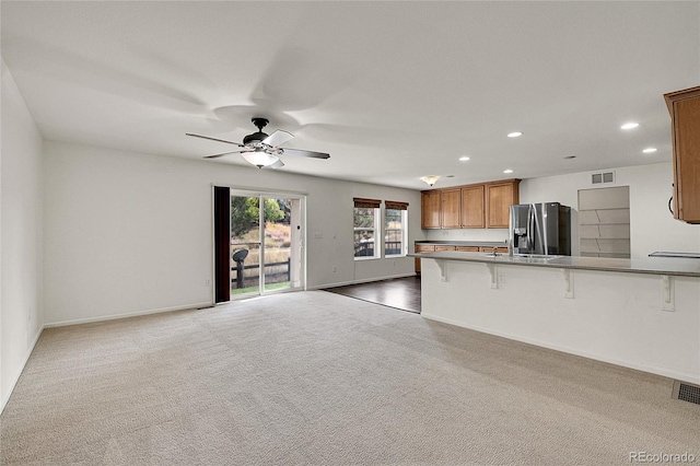 kitchen featuring ceiling fan, kitchen peninsula, carpet, stainless steel refrigerator with ice dispenser, and a kitchen bar