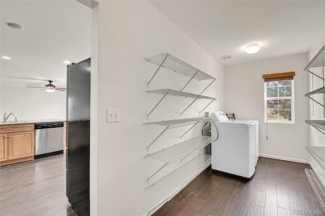 clothes washing area featuring dark hardwood / wood-style floors, washing machine and dryer, sink, and ceiling fan