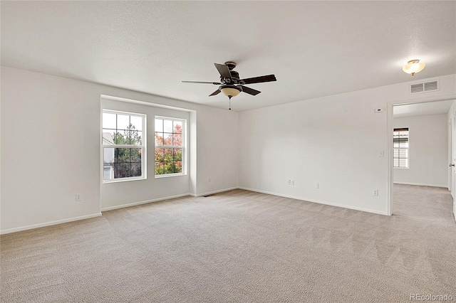 carpeted spare room featuring ceiling fan, a textured ceiling, and a healthy amount of sunlight