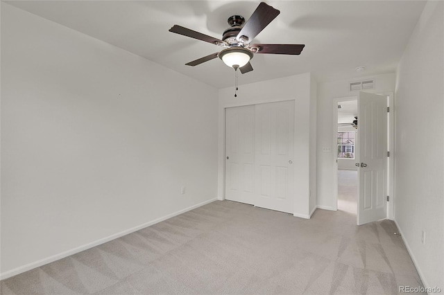 unfurnished bedroom featuring light carpet, ceiling fan, and a closet