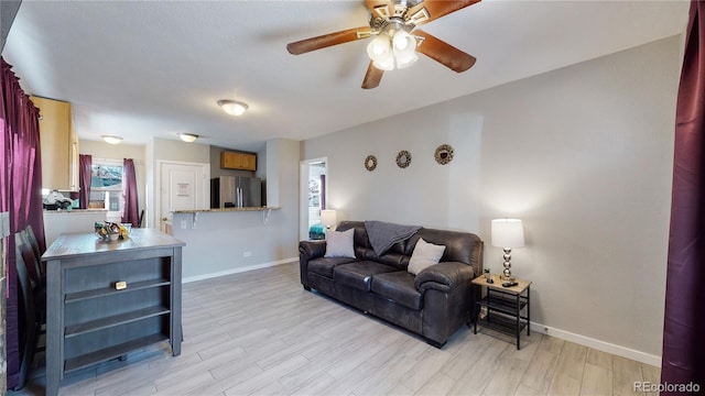 living area with ceiling fan, light wood-style flooring, and baseboards