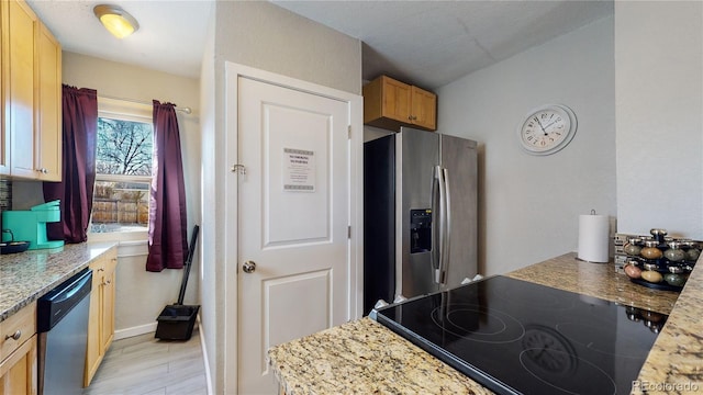 kitchen with light wood-style floors, light stone counters, and stainless steel appliances