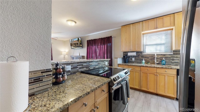 kitchen with decorative backsplash, appliances with stainless steel finishes, light stone countertops, light brown cabinets, and a sink