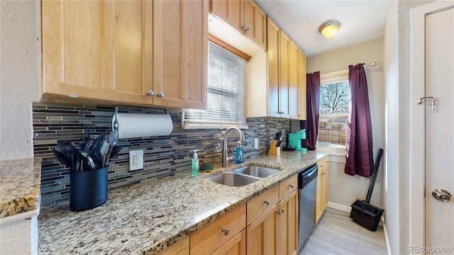 kitchen with light stone countertops, dishwasher, decorative backsplash, and a sink