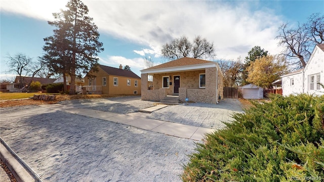 view of front of house featuring stone siding, driveway, and an outdoor structure