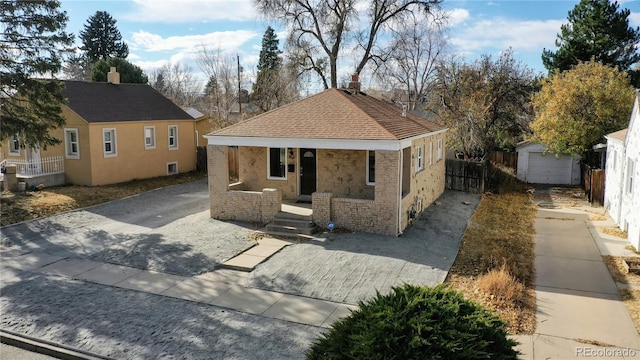 view of front of house with covered porch, driveway, an outdoor structure, and fence