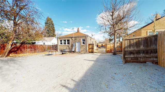 back of property with a fenced backyard and a chimney