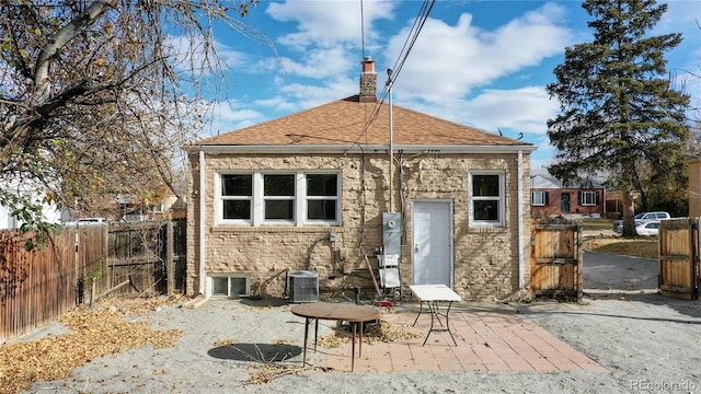 back of house with a chimney, roof with shingles, fence, a patio area, and central AC