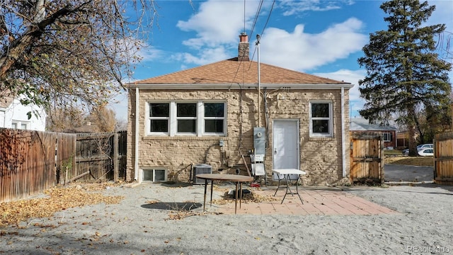 rear view of house featuring roof with shingles, a chimney, central AC, a patio area, and fence