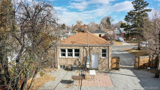 rear view of property with central air condition unit, fence, roof with shingles, a chimney, and a patio area