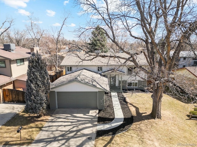 view of front of property featuring fence, driveway, an attached garage, a shingled roof, and a residential view