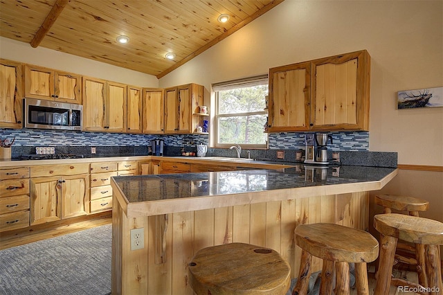 114 Star Ln, Bailey, CO 80421 - kitchen featuring stainless steel microwave, a peninsula, a sink, vaulted ceiling, and backsplash