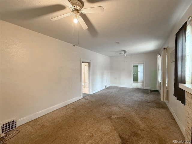 carpeted spare room featuring visible vents, baseboards, and a ceiling fan