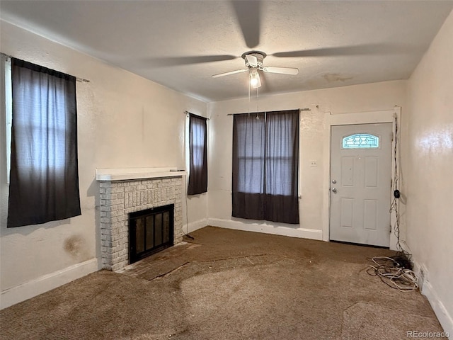 carpeted foyer entrance with a textured ceiling, a fireplace, baseboards, and ceiling fan