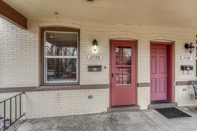 view of exterior entry with a porch and brick siding