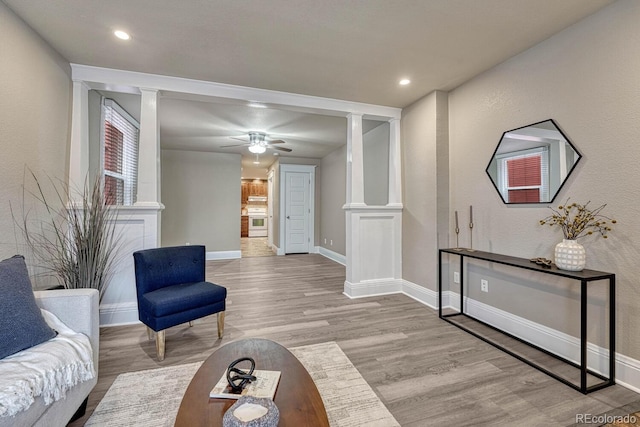 living room featuring ornate columns, baseboards, and wood finished floors