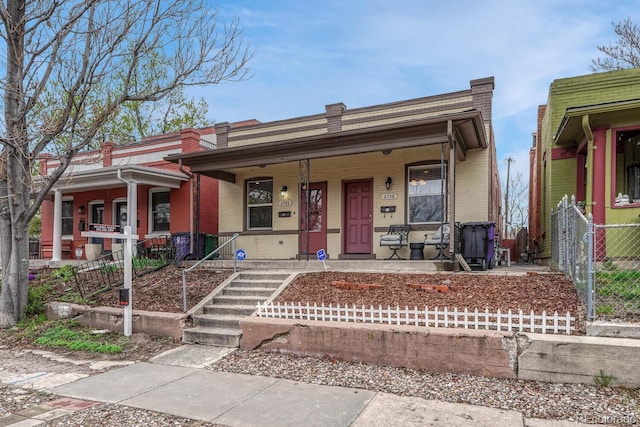 view of front of property with a porch, fence, and brick siding