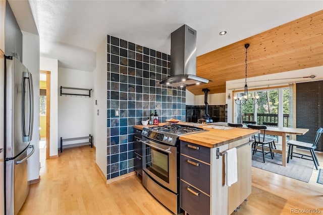 kitchen with ventilation hood, tile walls, appliances with stainless steel finishes, wood counters, and hanging light fixtures