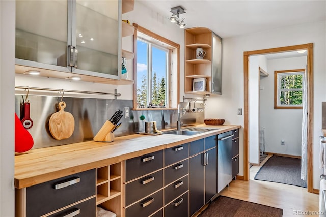 kitchen featuring dishwasher, a wealth of natural light, light hardwood / wood-style floors, and wood counters