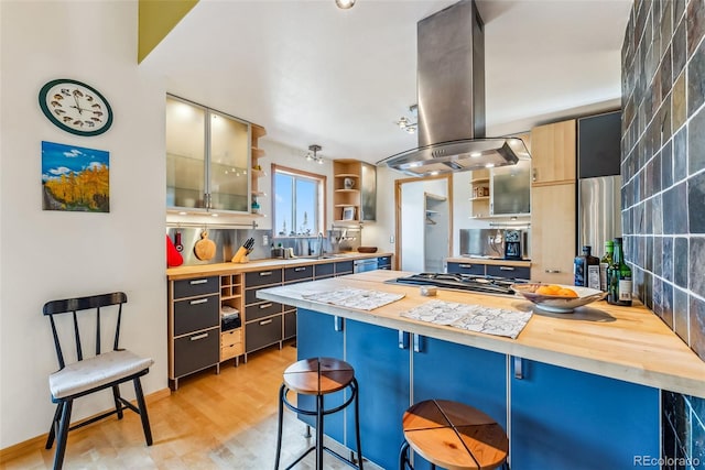 kitchen featuring light hardwood / wood-style floors, stainless steel gas cooktop, a kitchen breakfast bar, island exhaust hood, and butcher block countertops