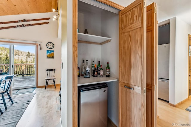 bar featuring light wood-type flooring, lofted ceiling, wooden ceiling, and stainless steel fridge