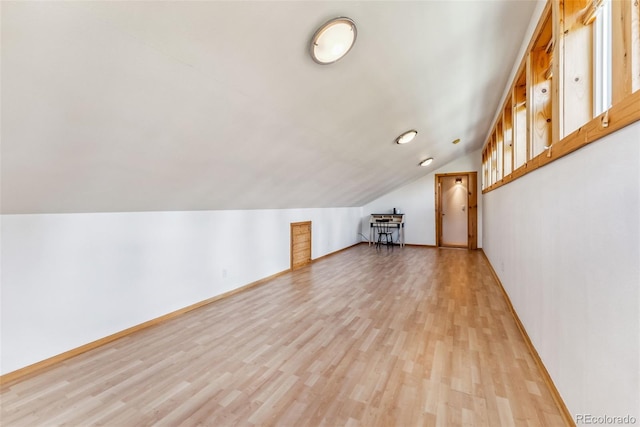 additional living space with light hardwood / wood-style flooring and vaulted ceiling