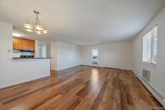 unfurnished living room featuring an inviting chandelier, a baseboard radiator, and wood finished floors