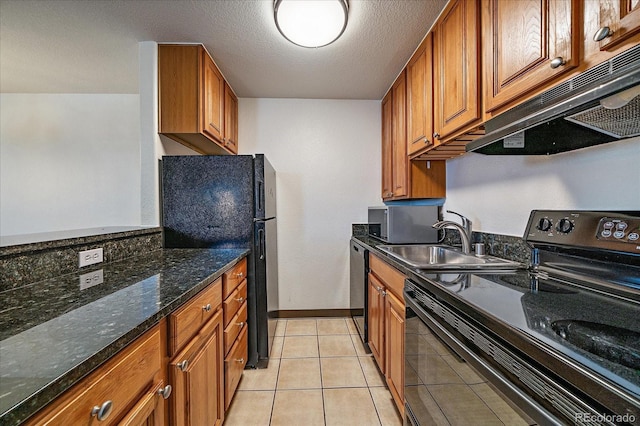 kitchen featuring under cabinet range hood, brown cabinets, a sink, dark stone countertops, and black appliances