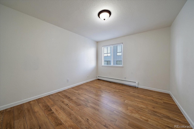 spare room with baseboards, baseboard heating, and hardwood / wood-style flooring