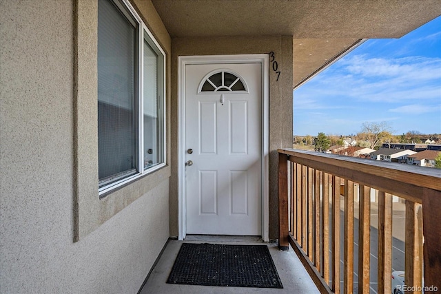entrance to property featuring a balcony and stucco siding